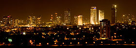 Night time picture of Tel Aviv showing many skyscrapers illuminating the city skyline